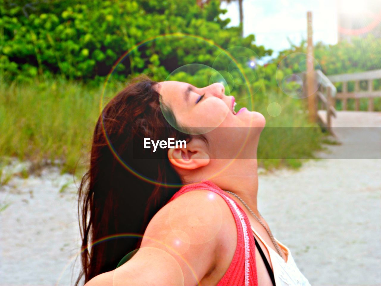 Side view of happy teenage girl standing with eyes closed at beach