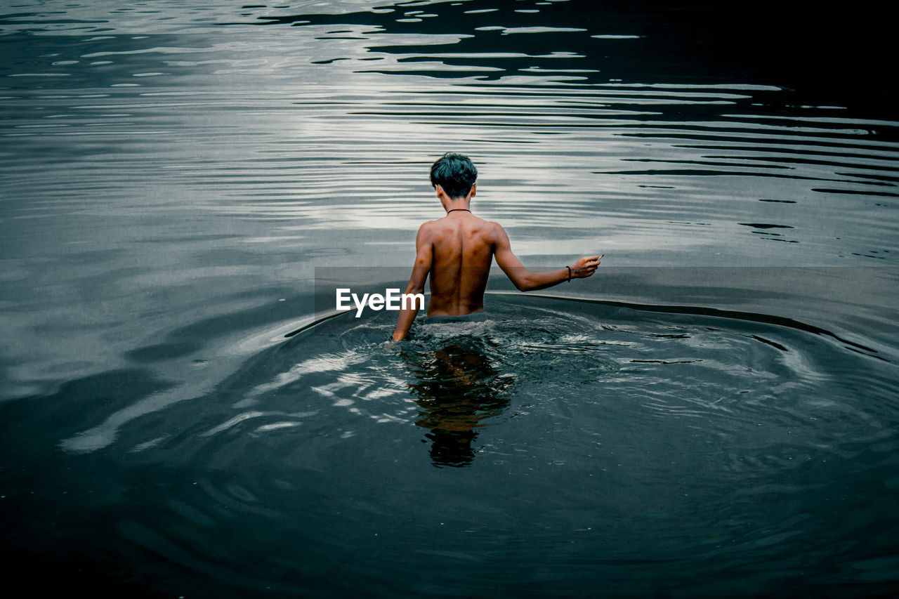 Rear view of shirtless man in lake