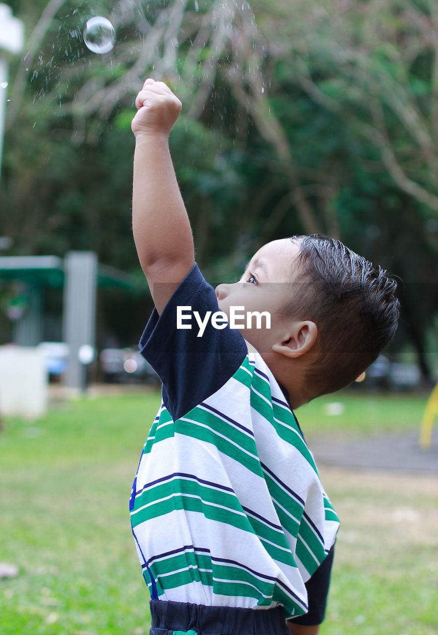 Close-up of boy playing with bubbles in park