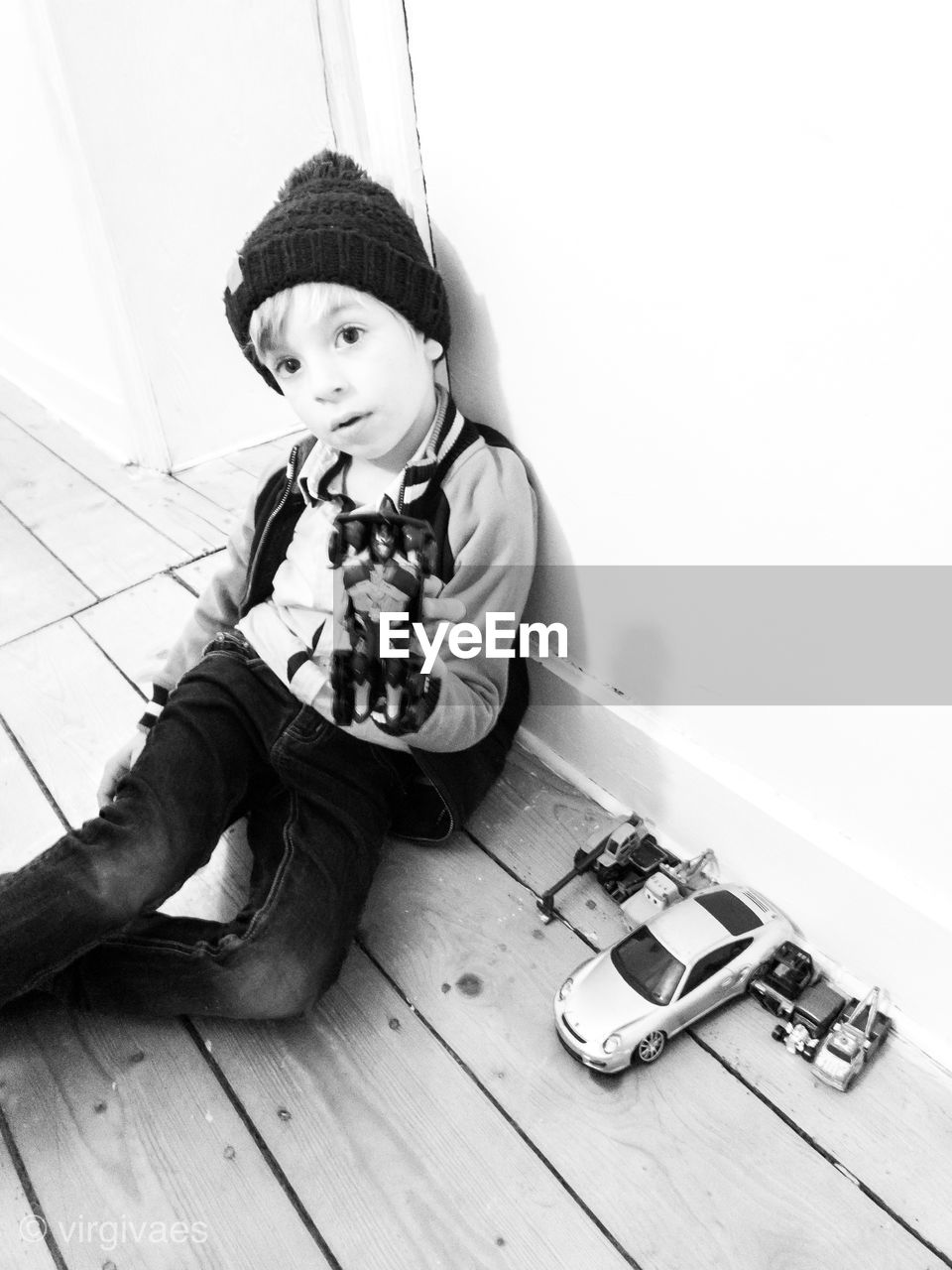 Portrait of cute boy holding toy while sitting on floor at home