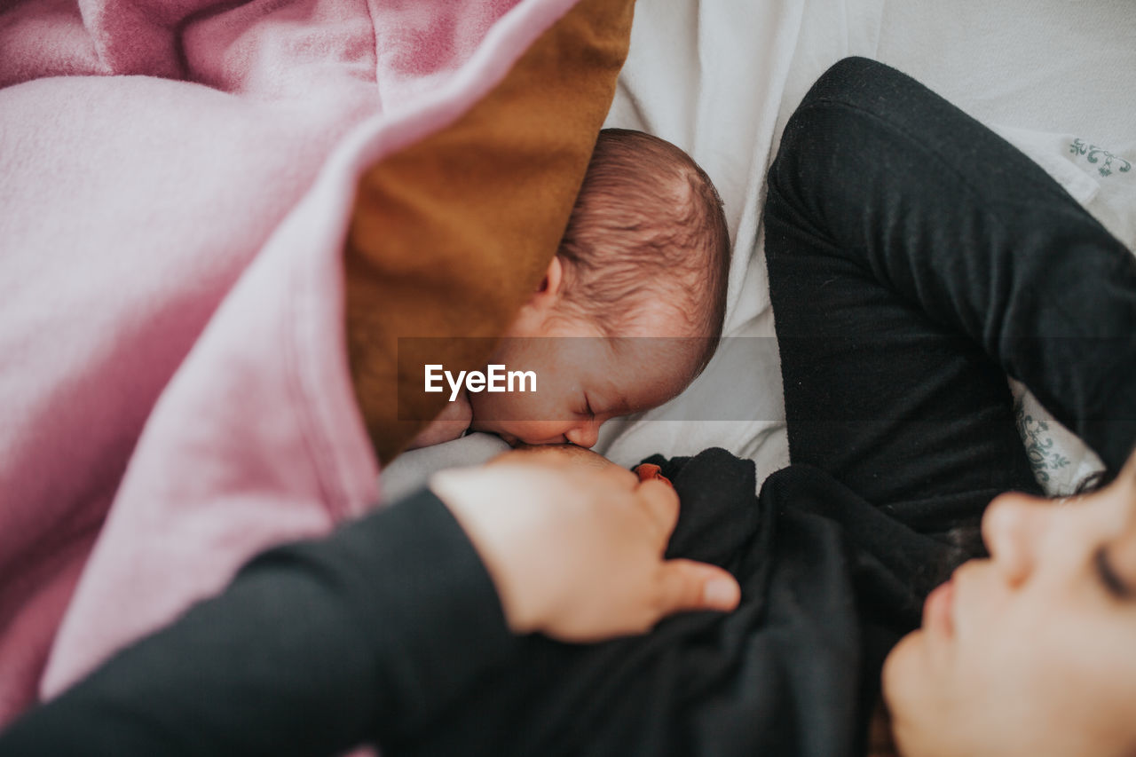 Mother breast feeding to daughter at home