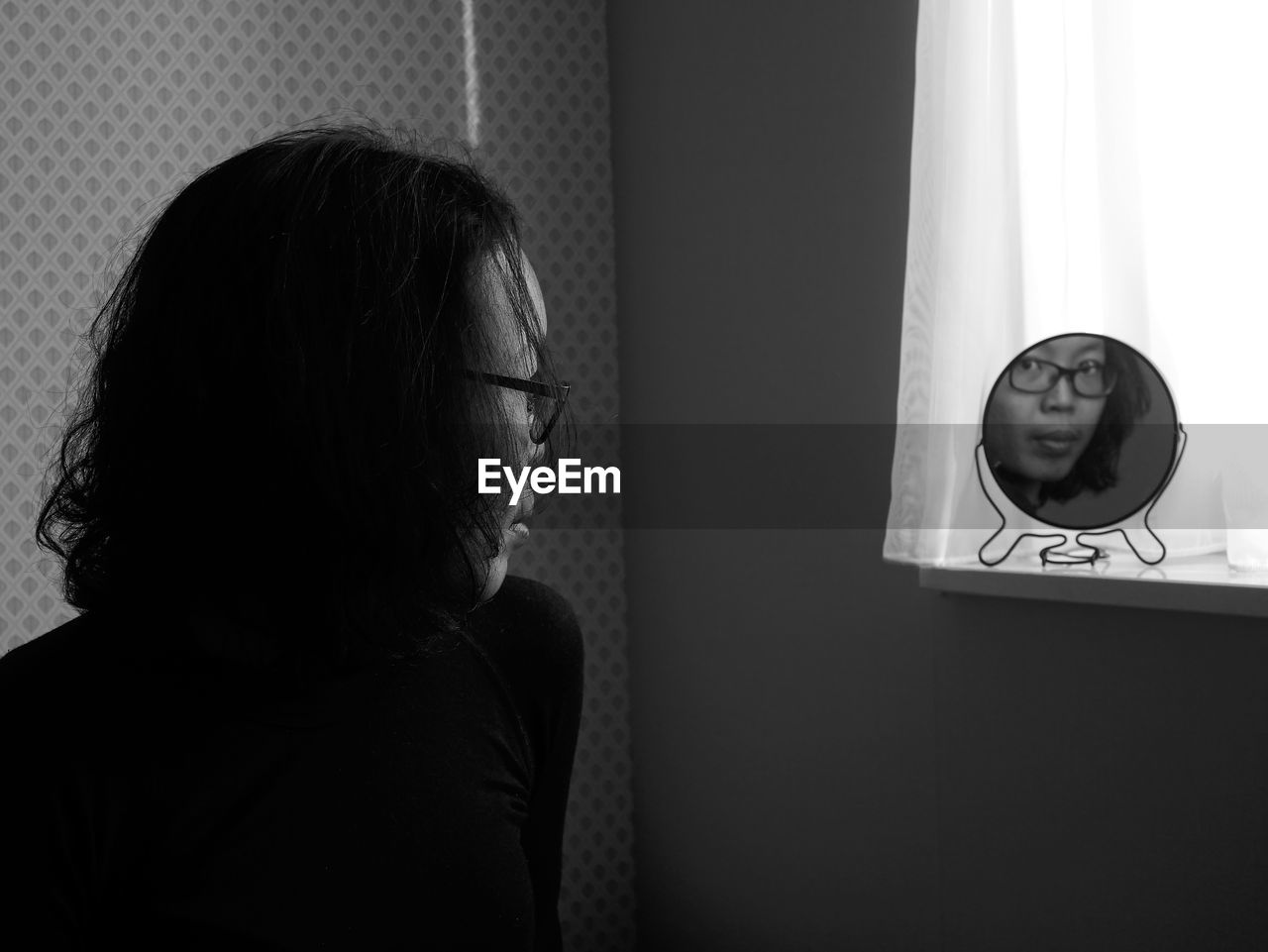 Woman looking into mirror at home