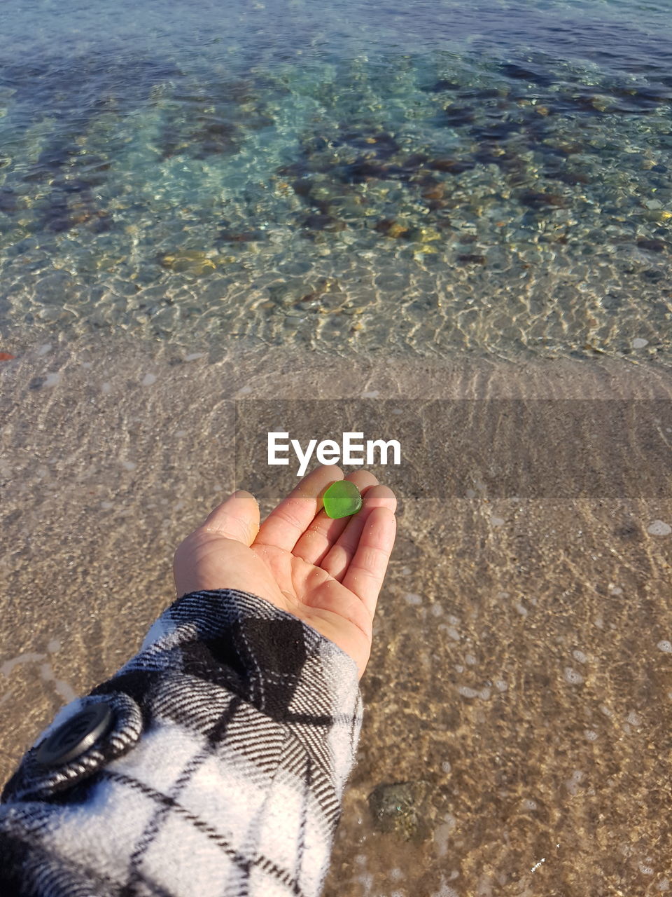 Cropped hand holding gemstone at beach