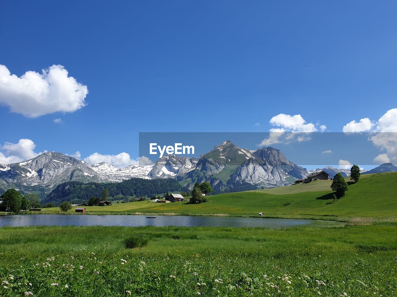 Scenic view of field, small lake and mountains against sky, swiss alps