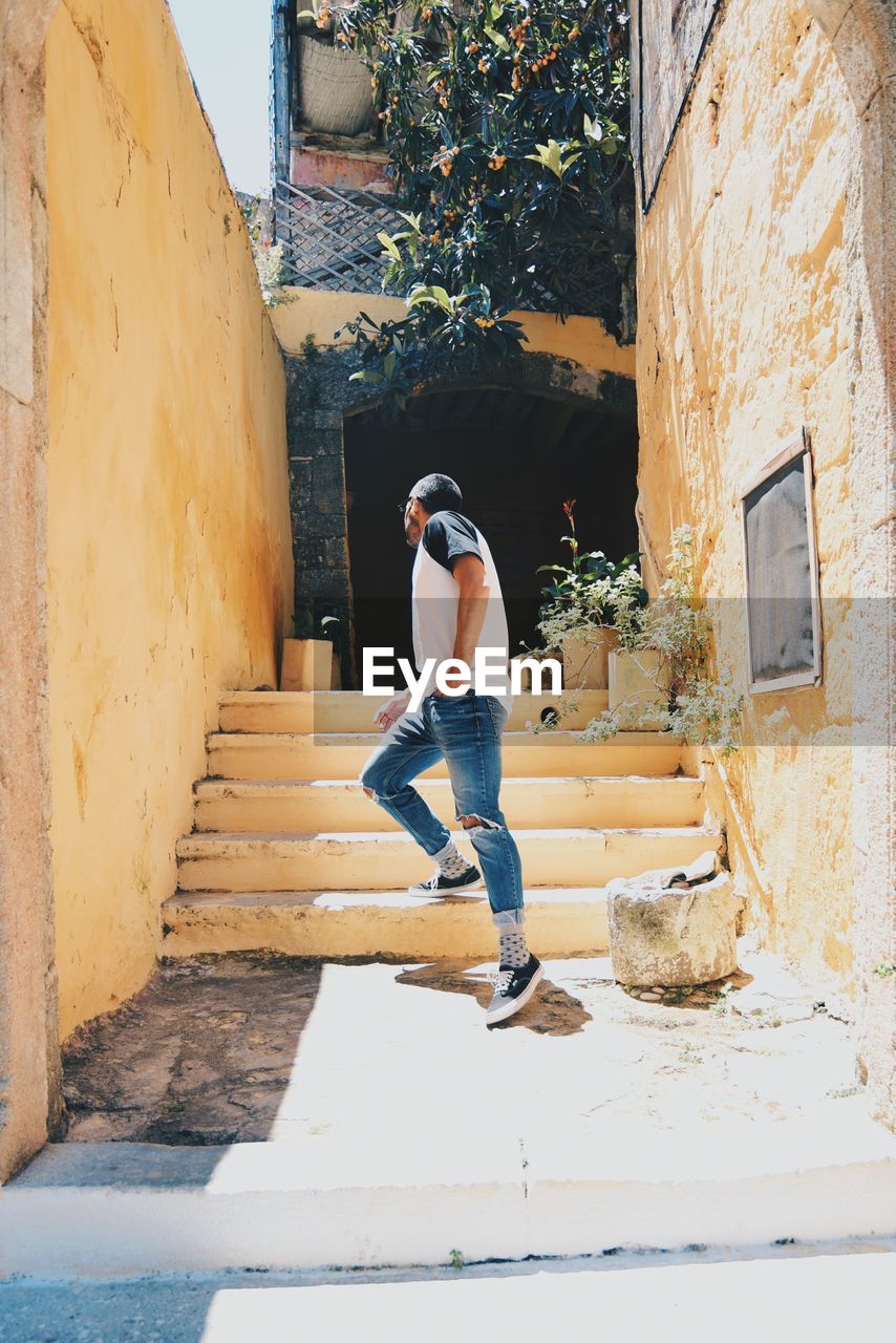 FULL LENGTH REAR VIEW OF MAN ON STAIRCASE OUTSIDE BUILDING