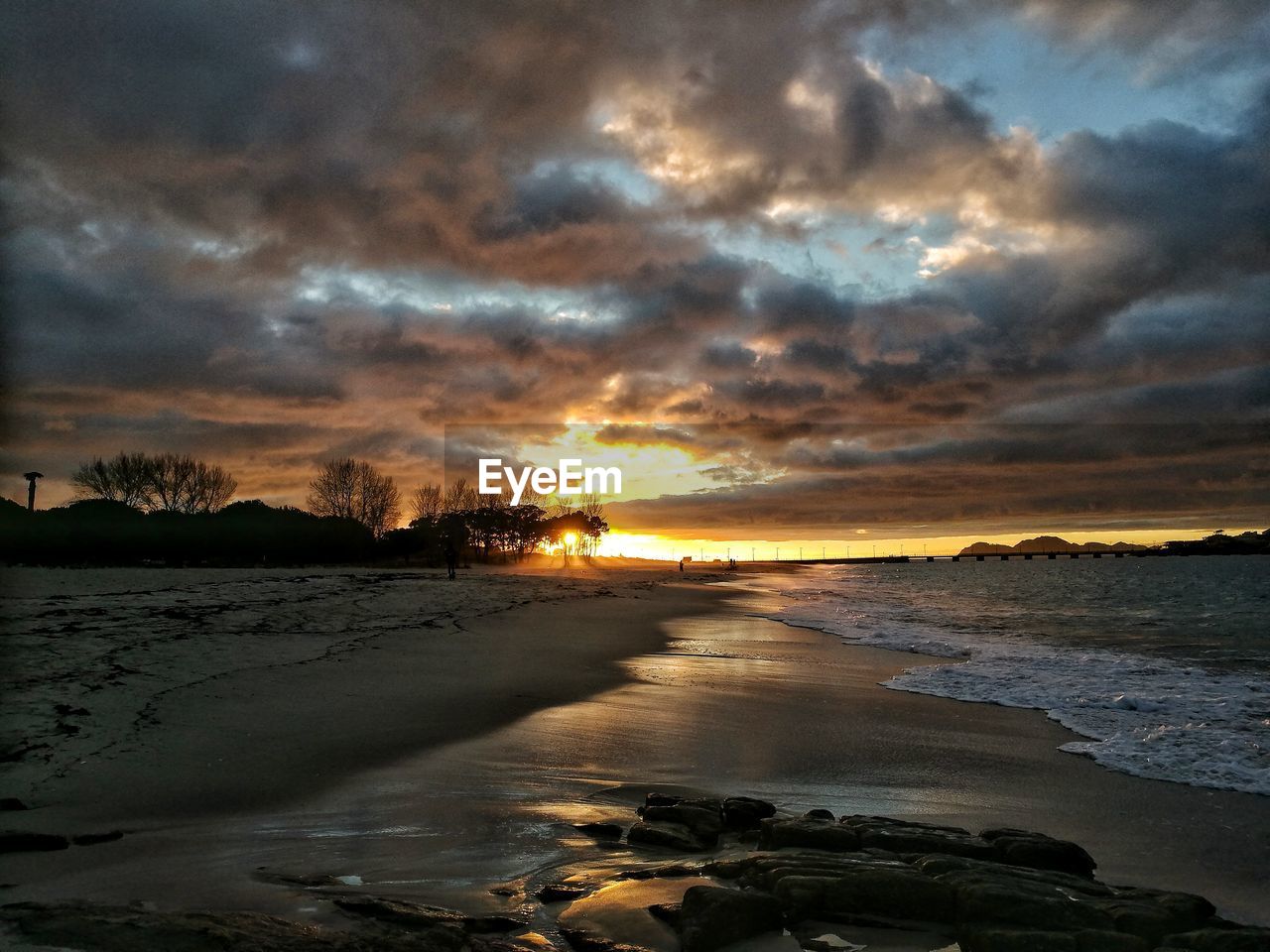 Scenic view of sea against dramatic sky during sunset