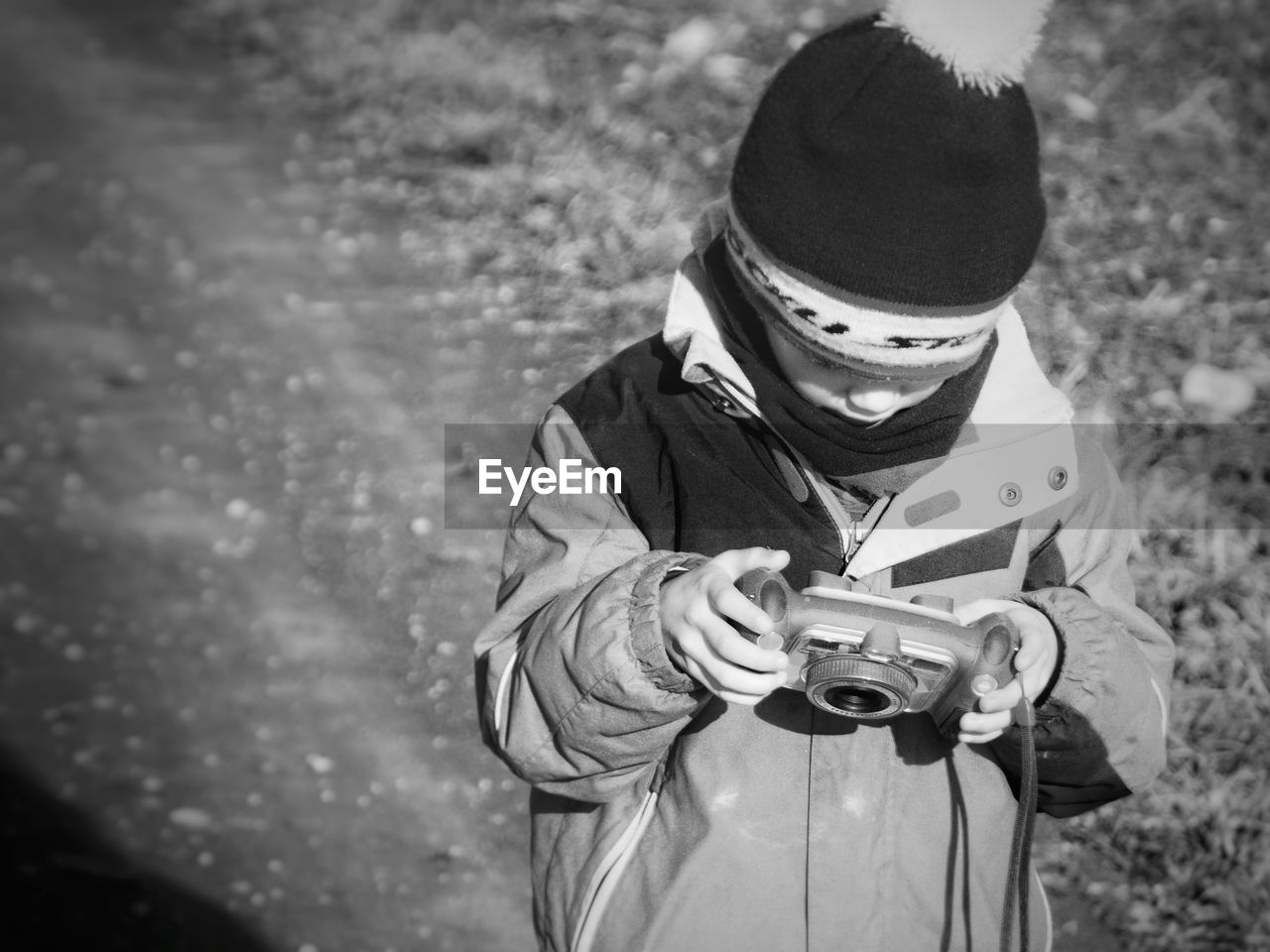 High angle view of boy holding camera on field