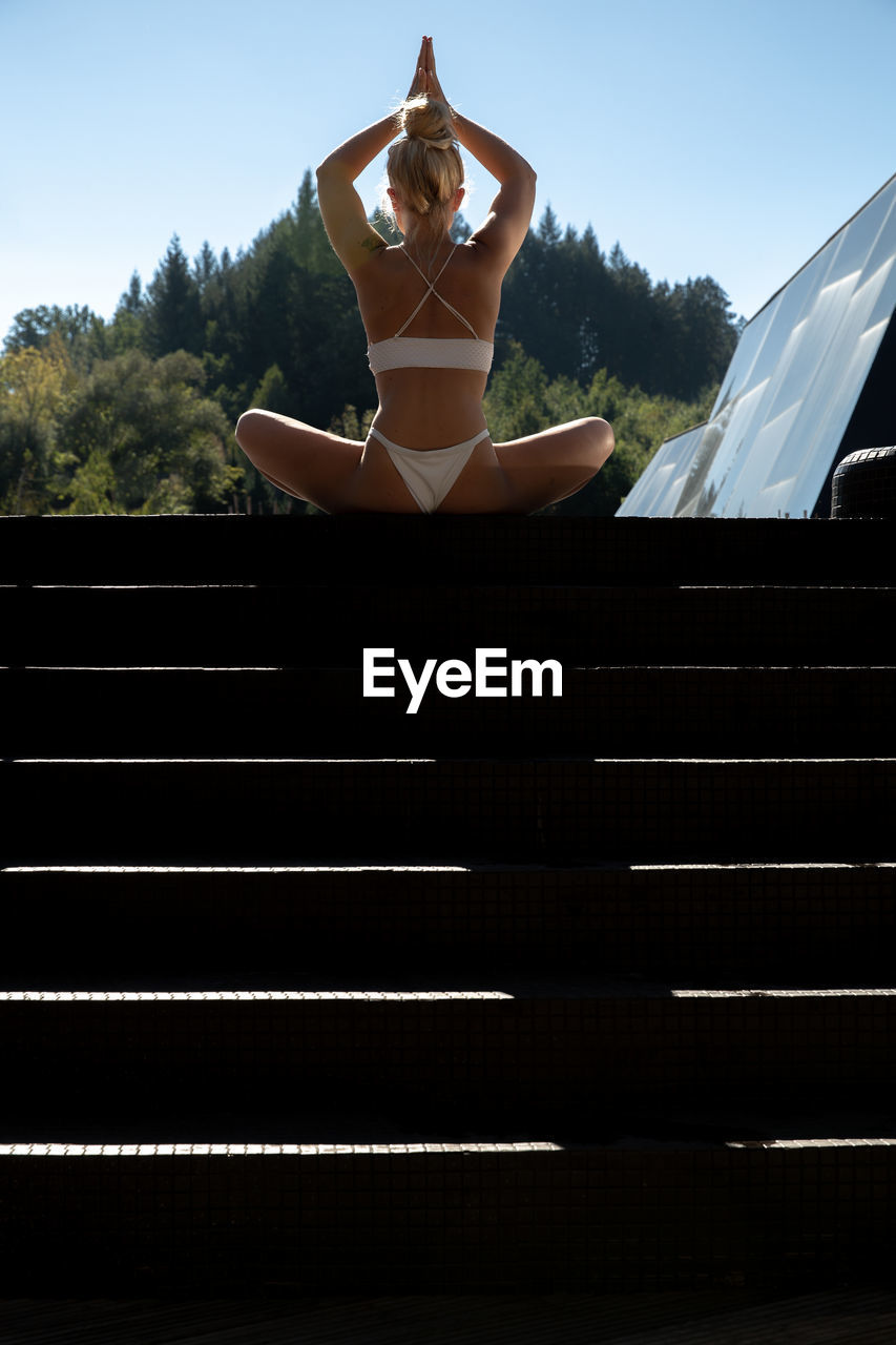 Woman doing yoga while sitting on staircase