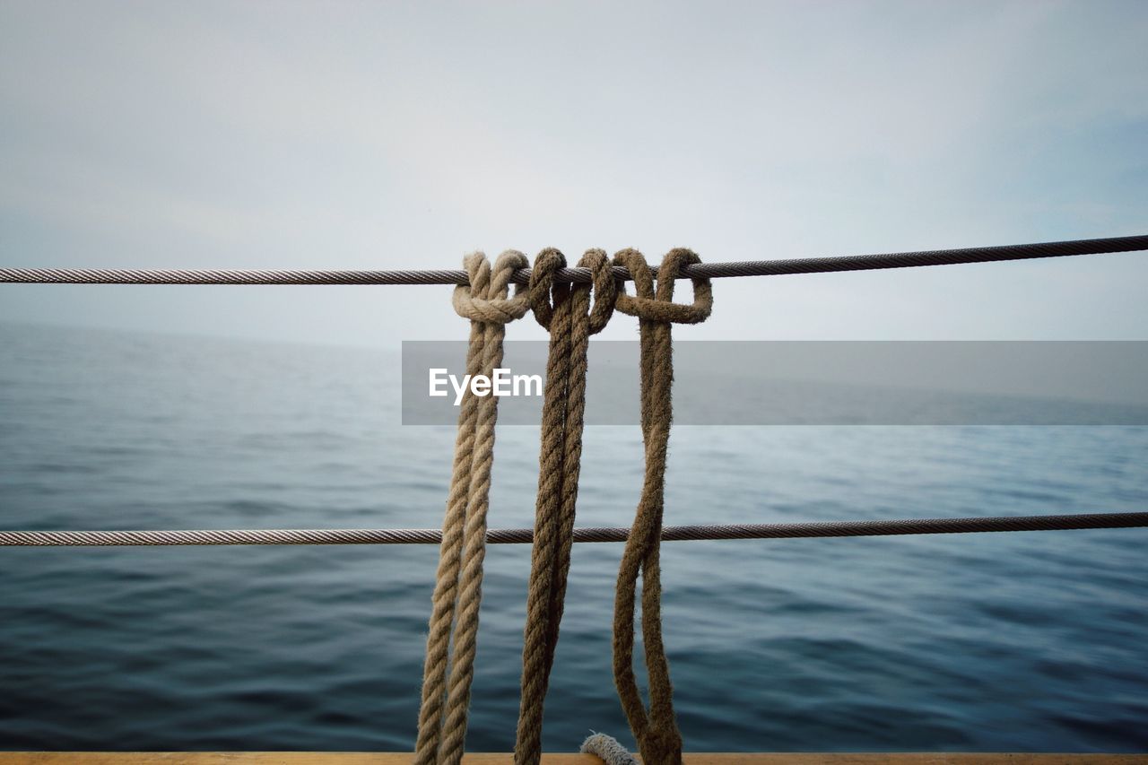 Close-up of ropes against calm sea