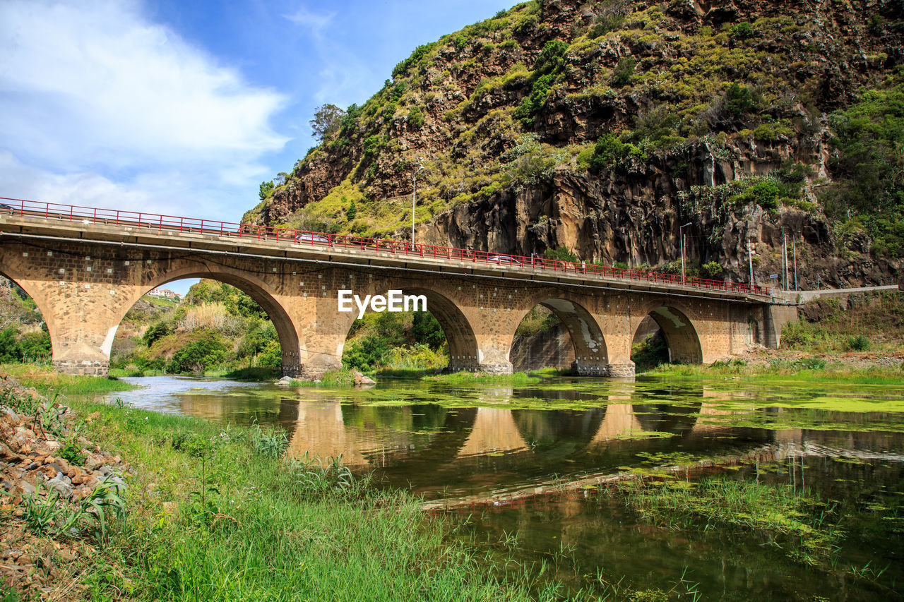 Arch bridge over river against sky