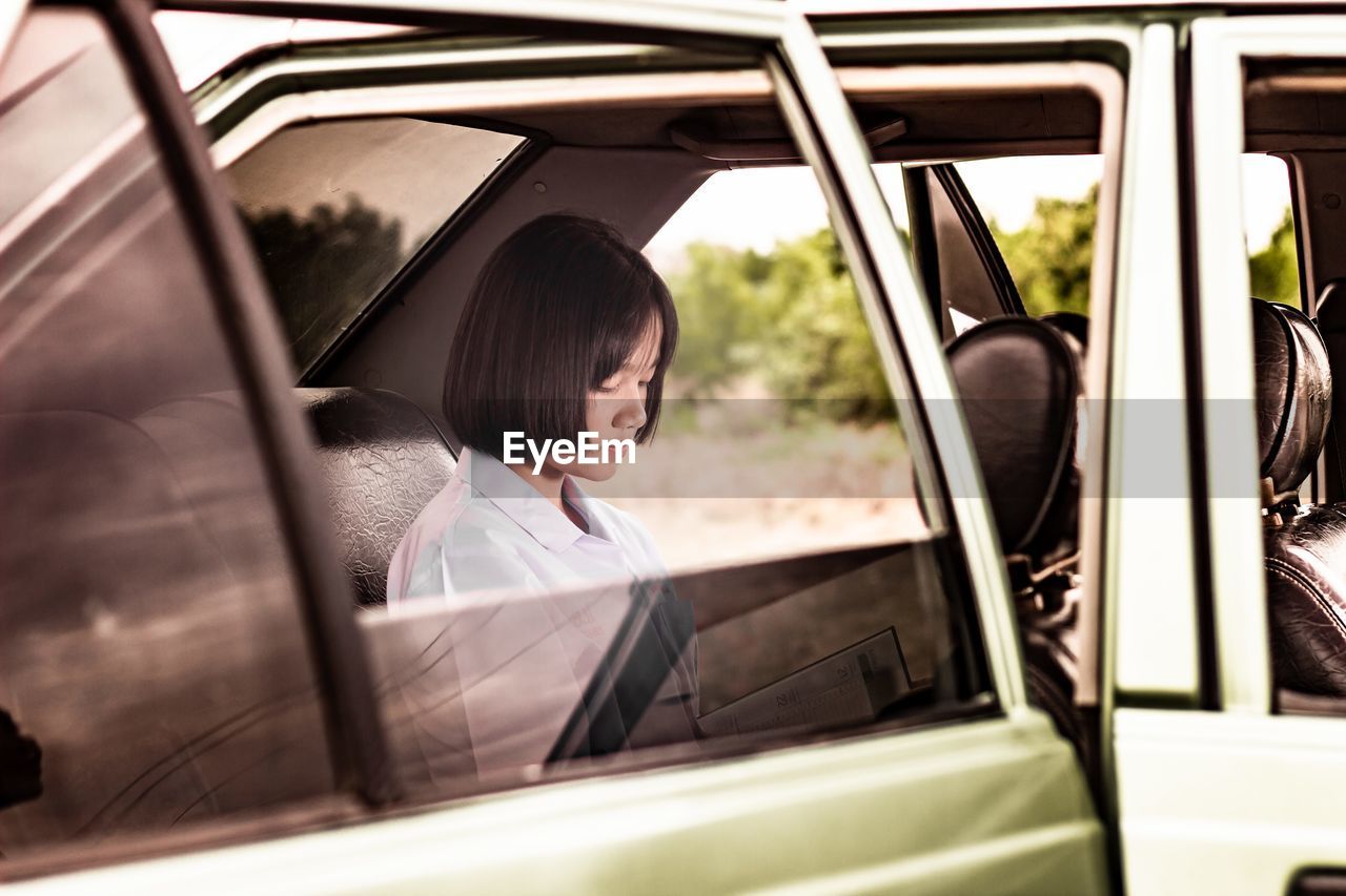 A little young women reading book and sitting in a car