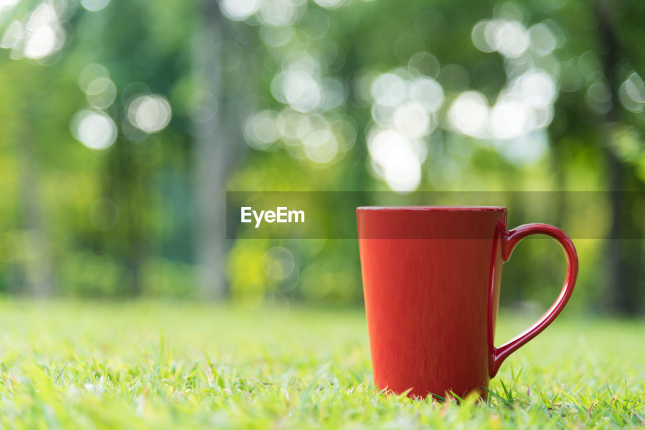 Close-up of red coffee cup on field