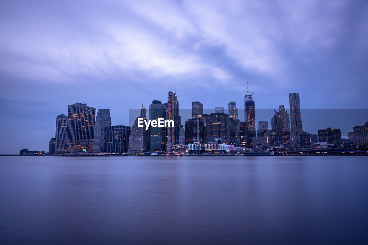 River by buildings against sky at dusk