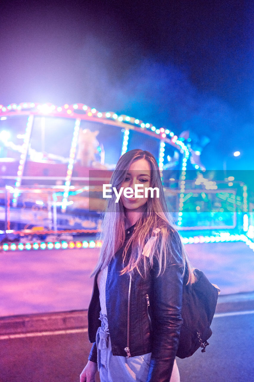 Smiling young woman standing at amusement park