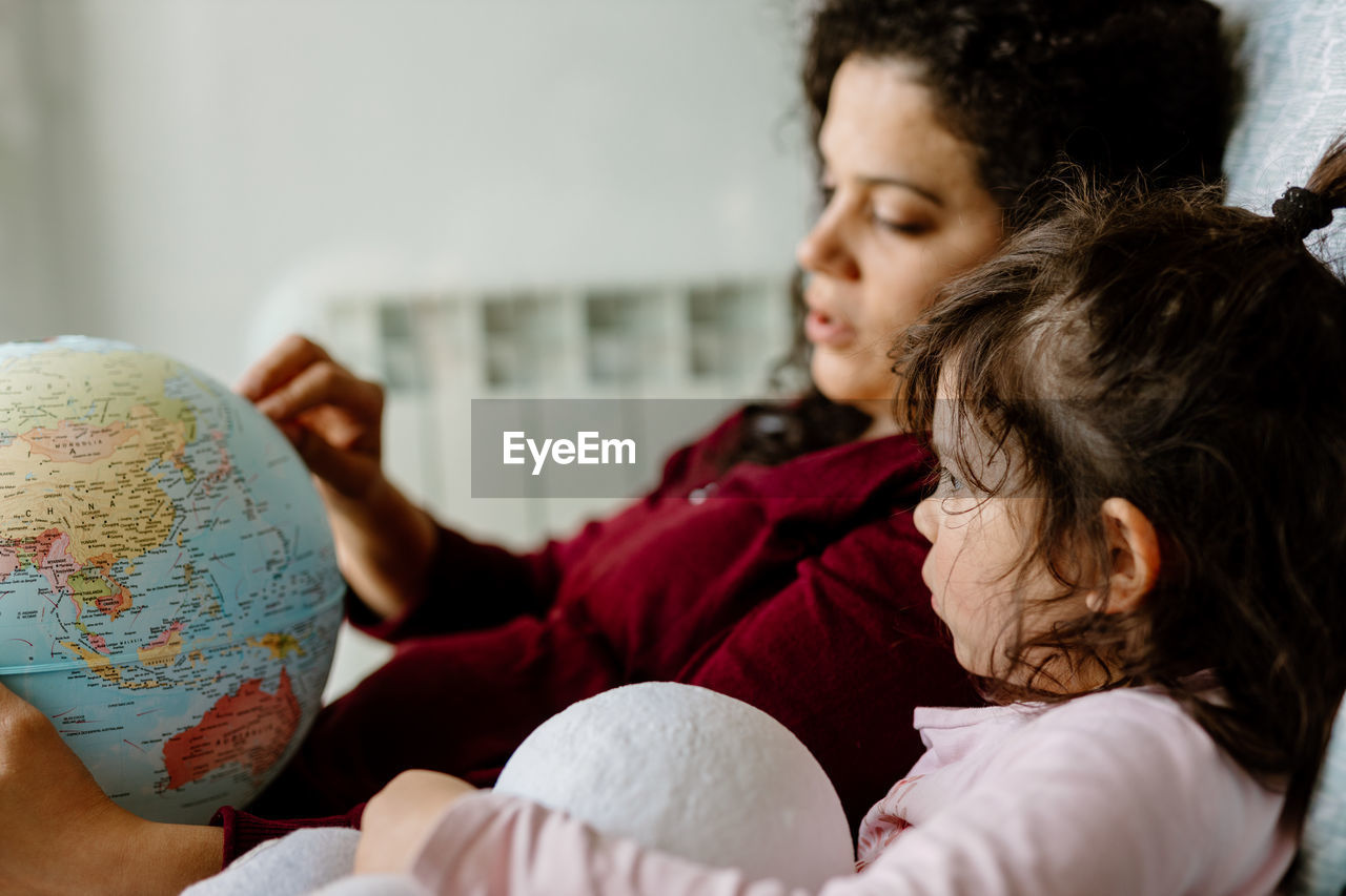 Mother and daughter playing with earth globe