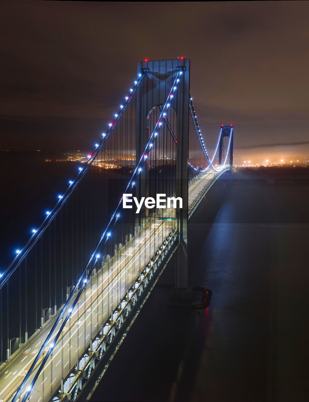 Illuminated bridge over river in city at night