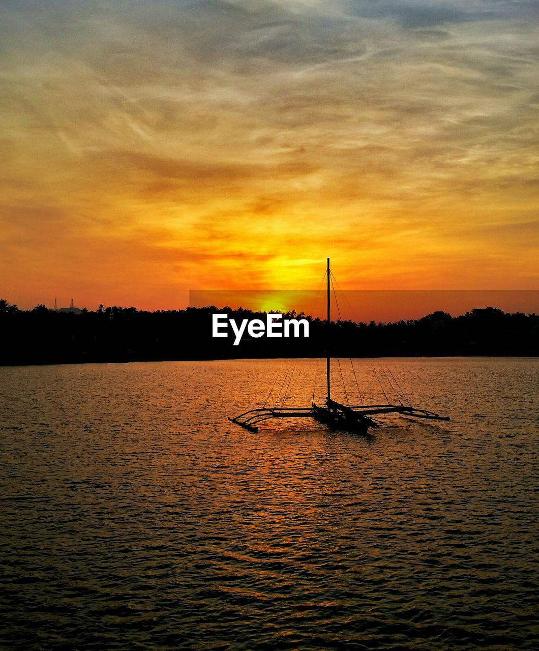 Outrigger boat on sea against sky during sunset