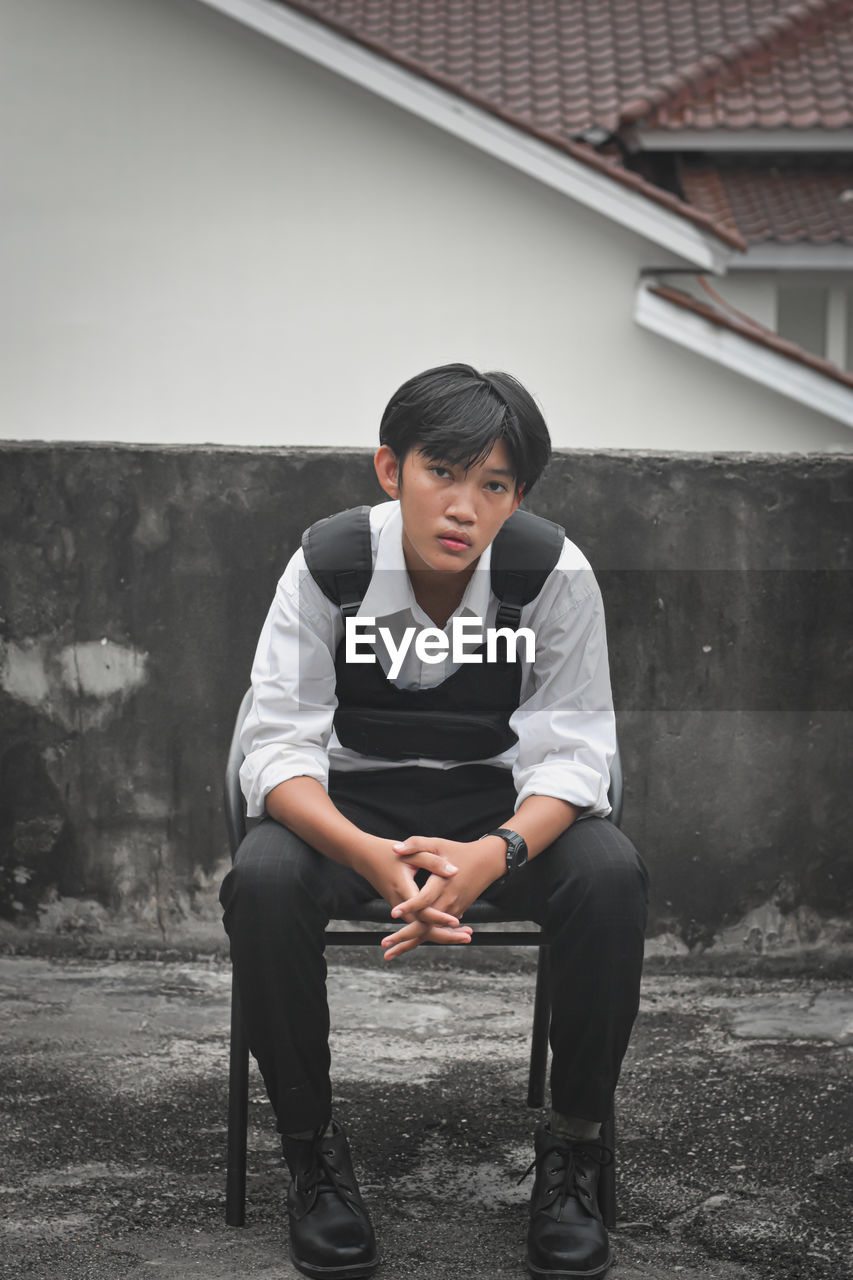 Side view of young man sitting on street