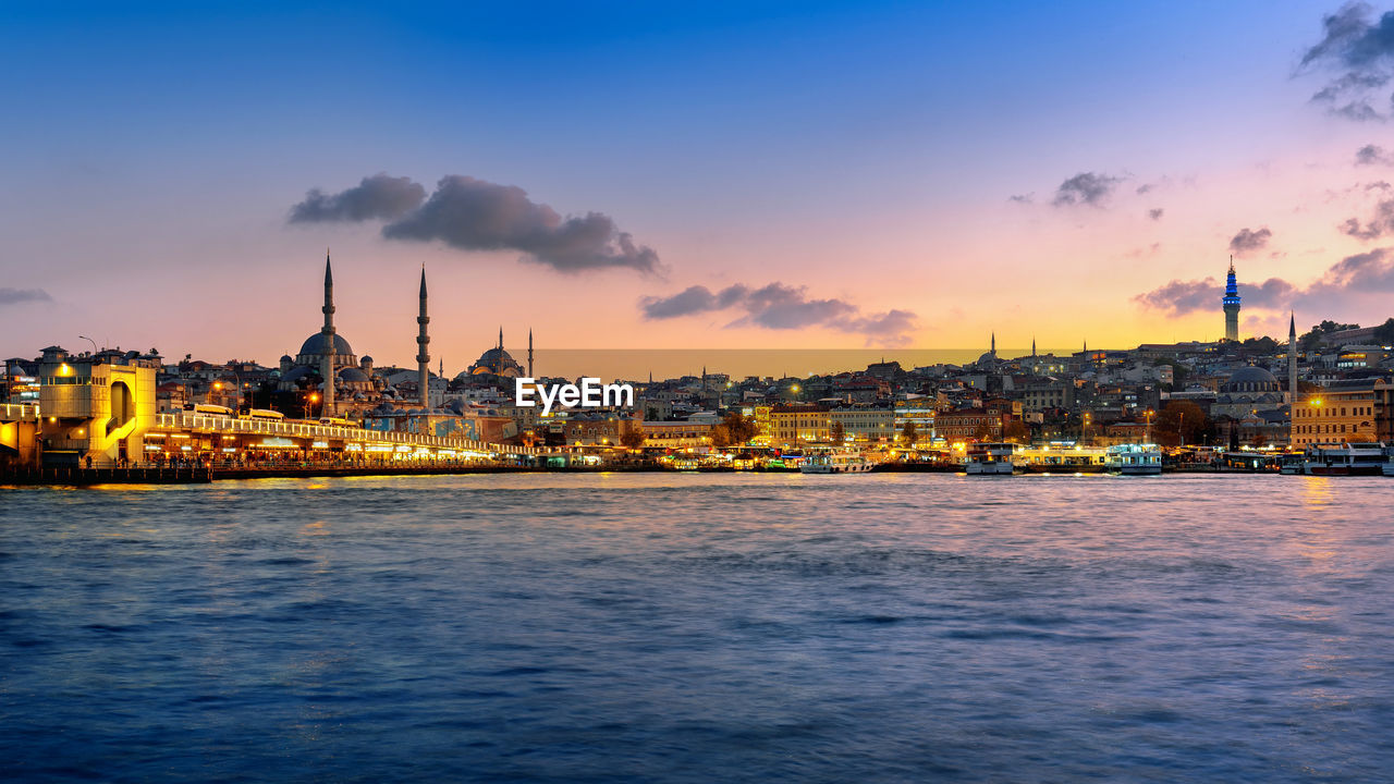 SCENIC VIEW OF SEA BY BUILDINGS AGAINST SKY AT DUSK