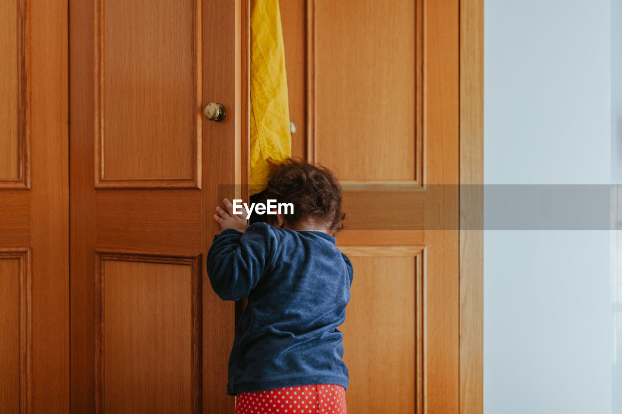 Rear view of baby girl looking through door