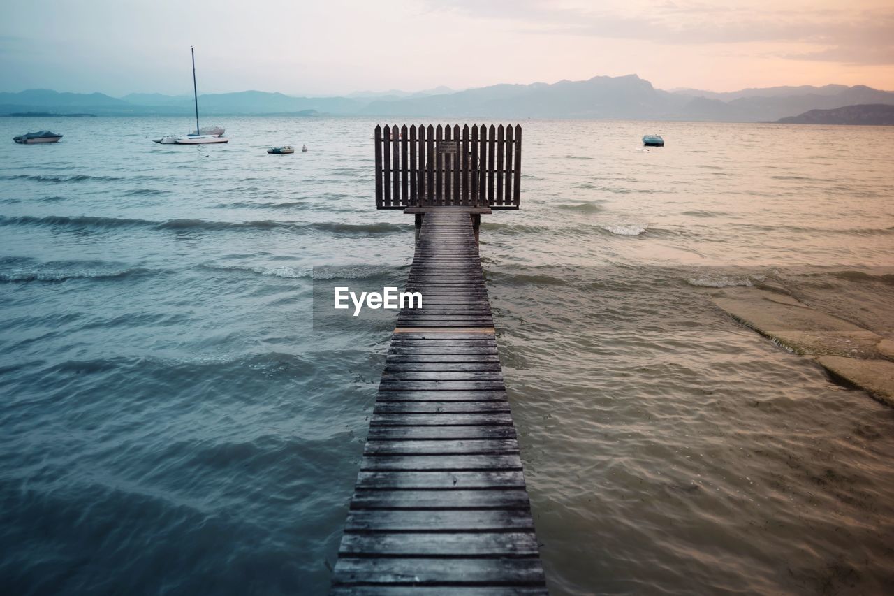 Wooden pier over lake garda during sunset