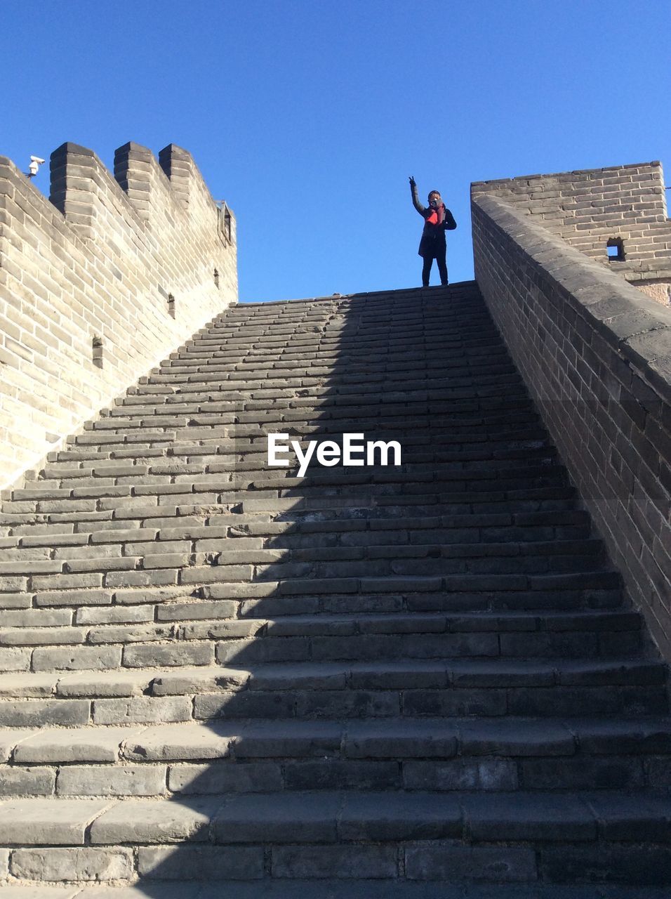 Low angle view of woman standing on staircase against clear sky
