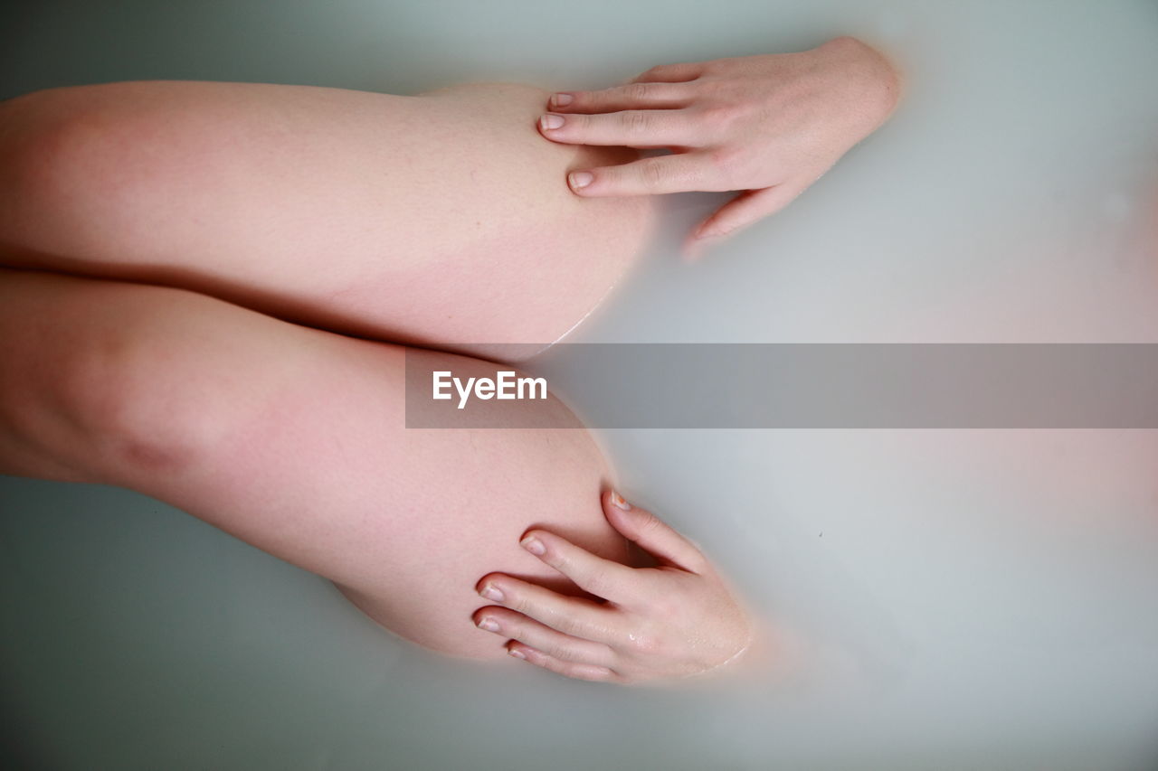 Midsection of young woman taking bath in bathtub