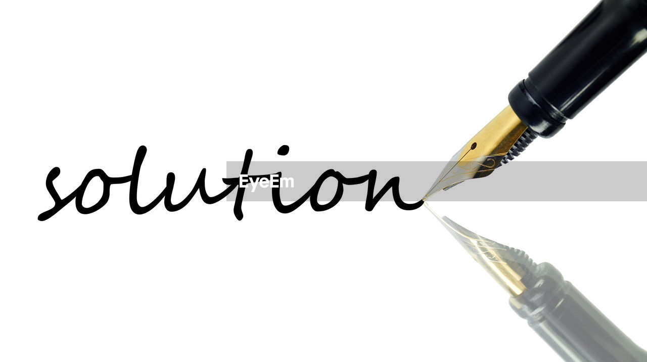 Close-up of pen with word solution on white background