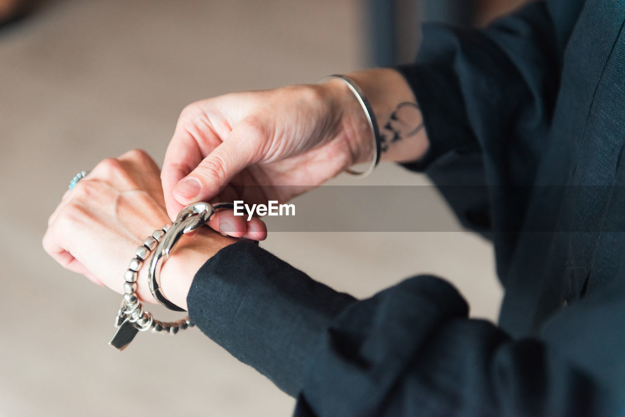 Fashion details - bracelets on the hand of a stylish woman with tattoo