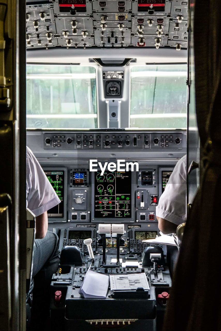 Midsection of pilot and co-pilot sitting in cockpit