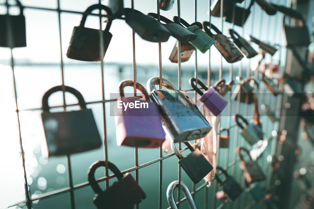 Padlocks hanging on railing against lake