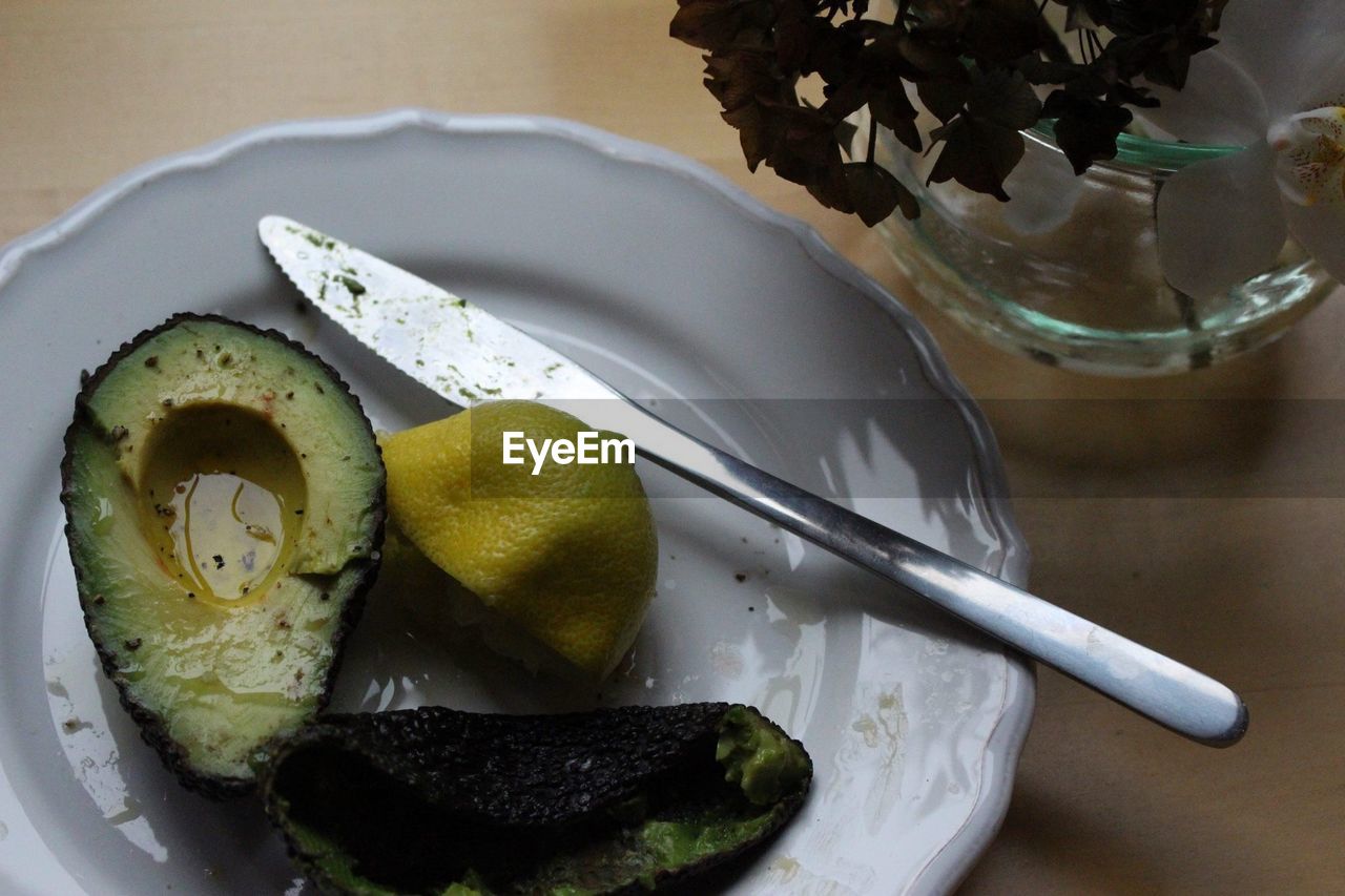 High angle view of avocado with lemon slice and table knife in plate
