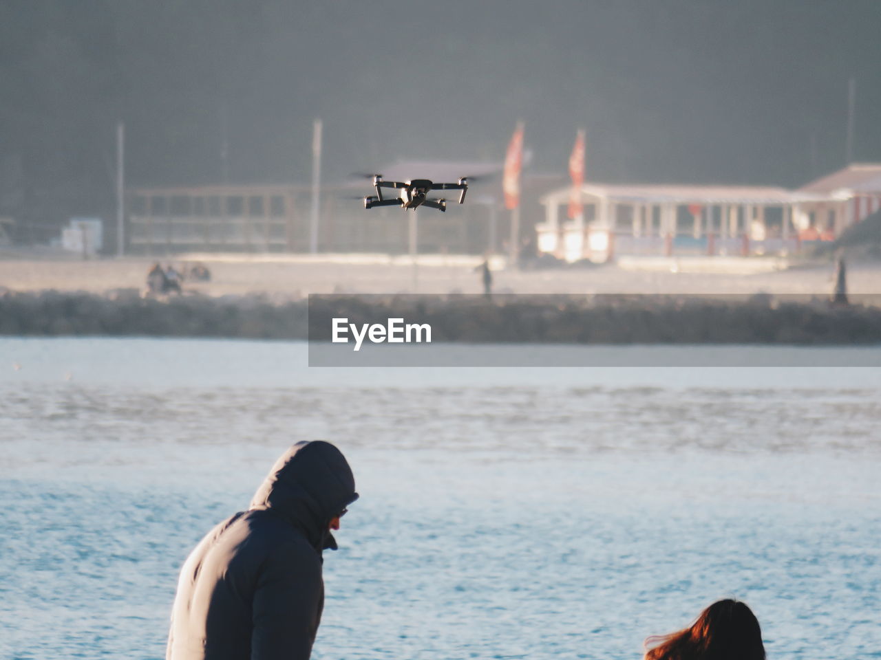 MAN FLYING OVER SEA AGAINST AIRPLANE