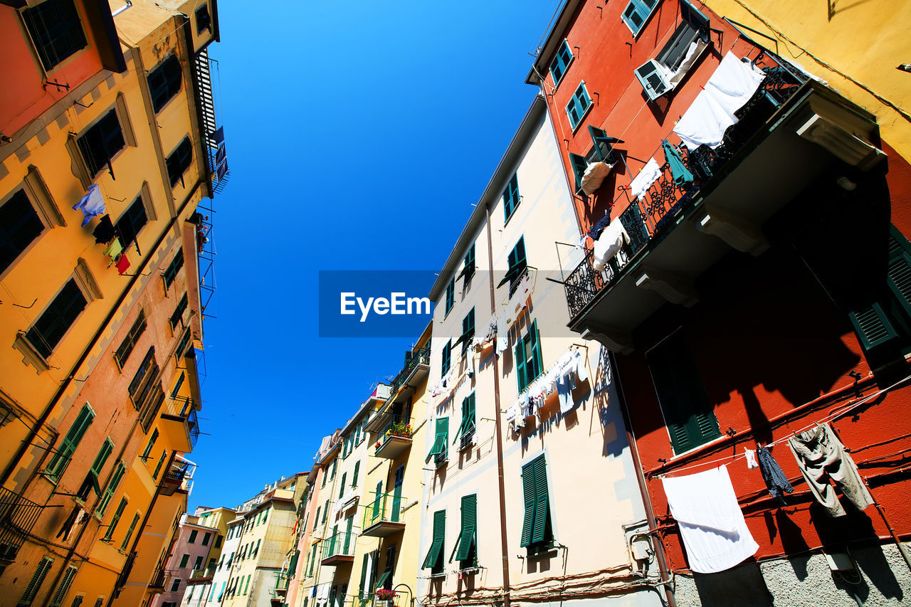 Low angle view of multi colored buildings in manarola against clear blue sky