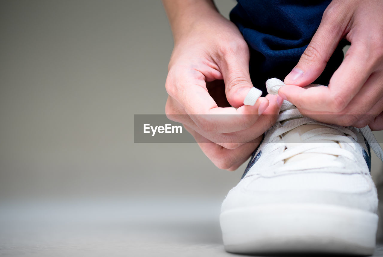 Low section of person tying shoelace