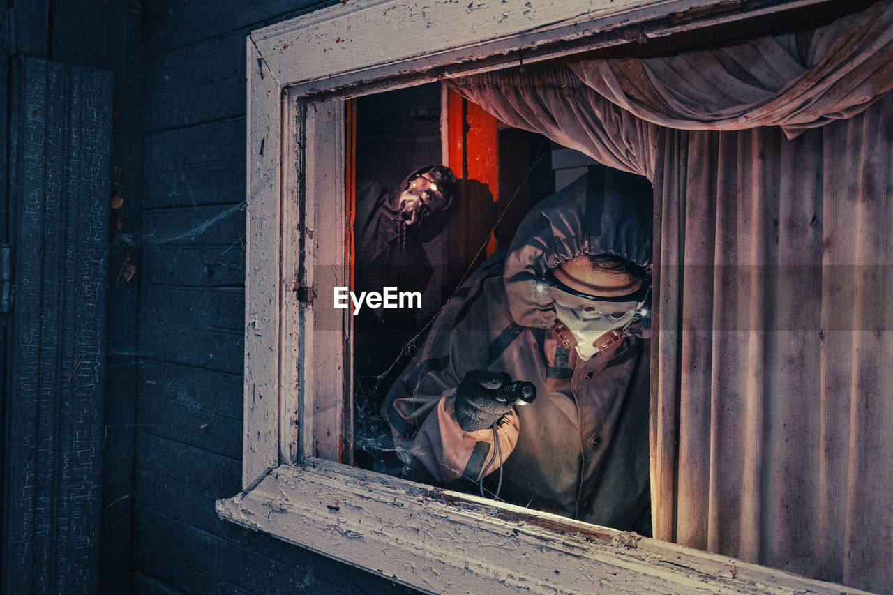 Fictional movie poster. people with flashlights, masks and protective clothing inspect old house. 