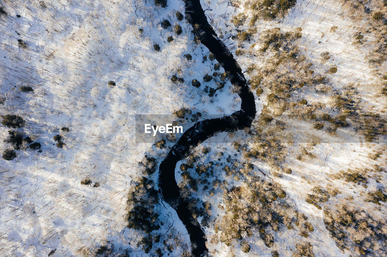 Aerial view of river amidst snow covered field