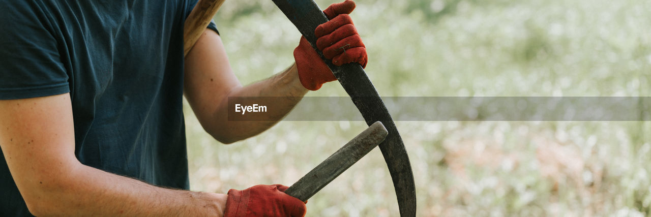 Mowing grass with scythe on farm. farmer man sharpening scythe with grass or whetstone for mowing