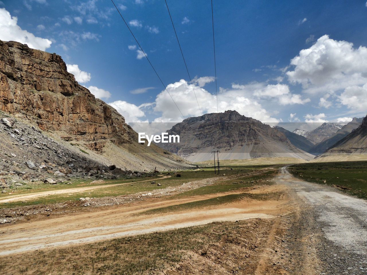 Scenic view of road by mountains against sky