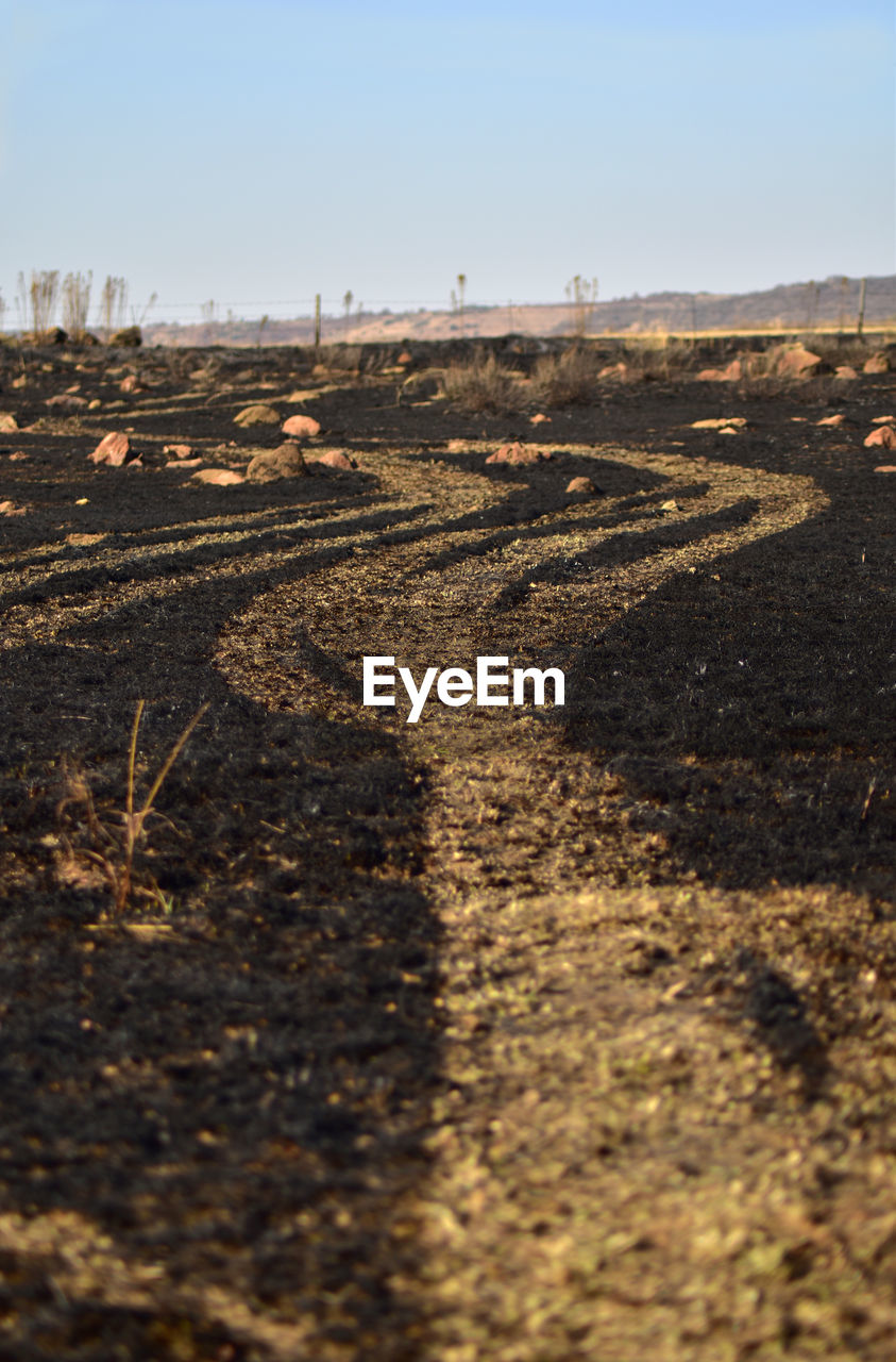 SURFACE LEVEL OF DIRT ROAD AGAINST SKY