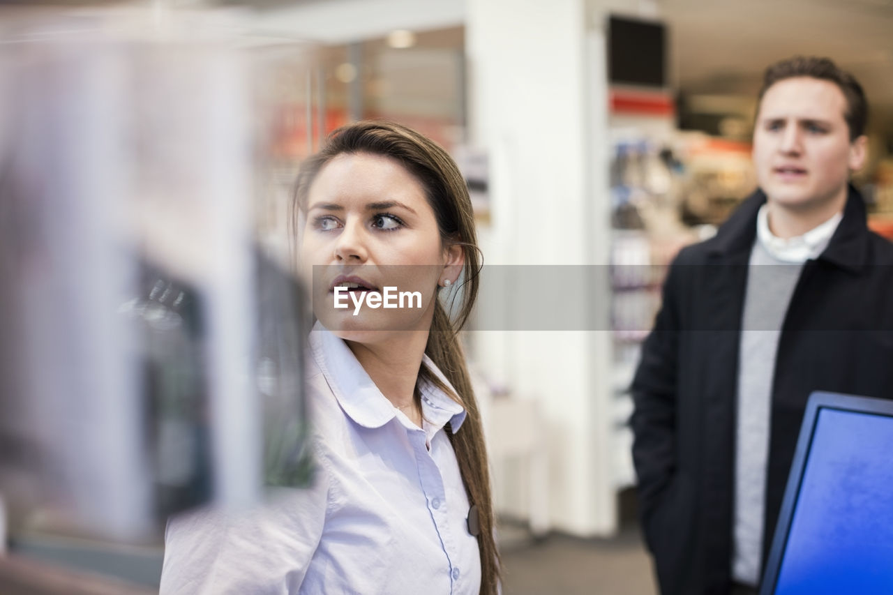 Saleswoman and male customer at cash counter in electronics store