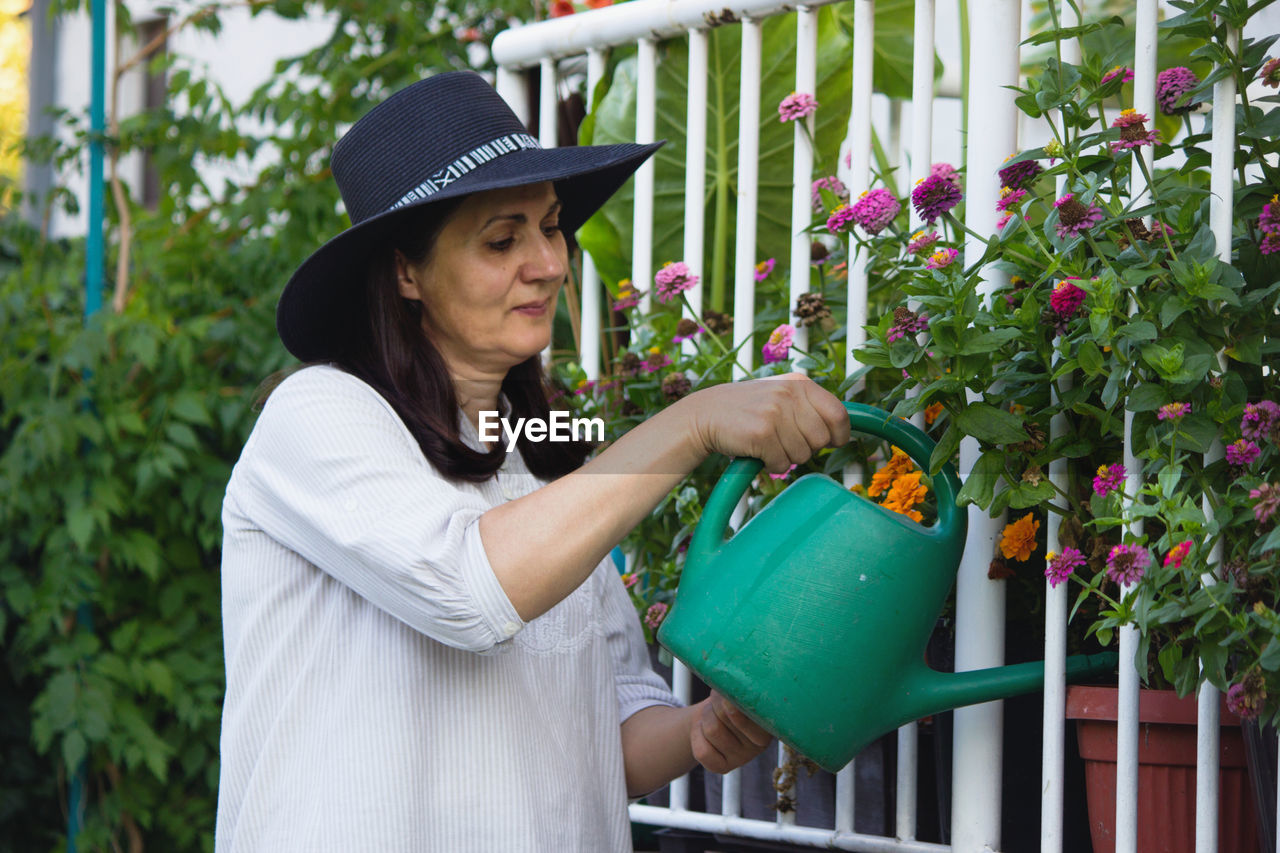 Woman watering while standing by plants