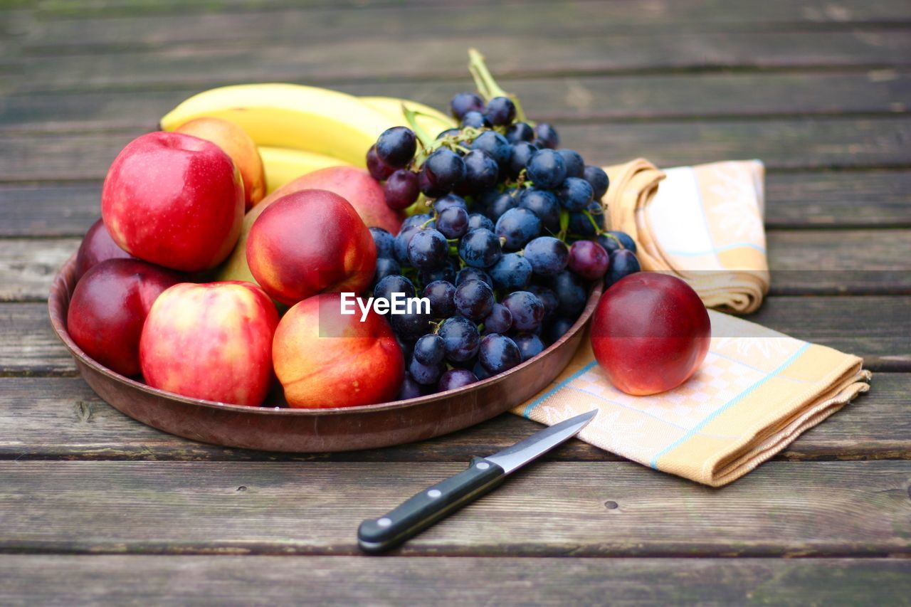 High angle view of fruits and knife on wooden table