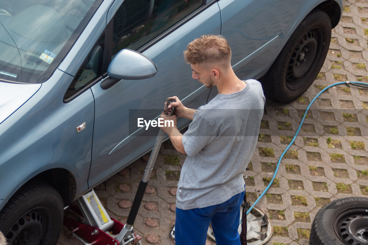 Rear view of man repairing car 