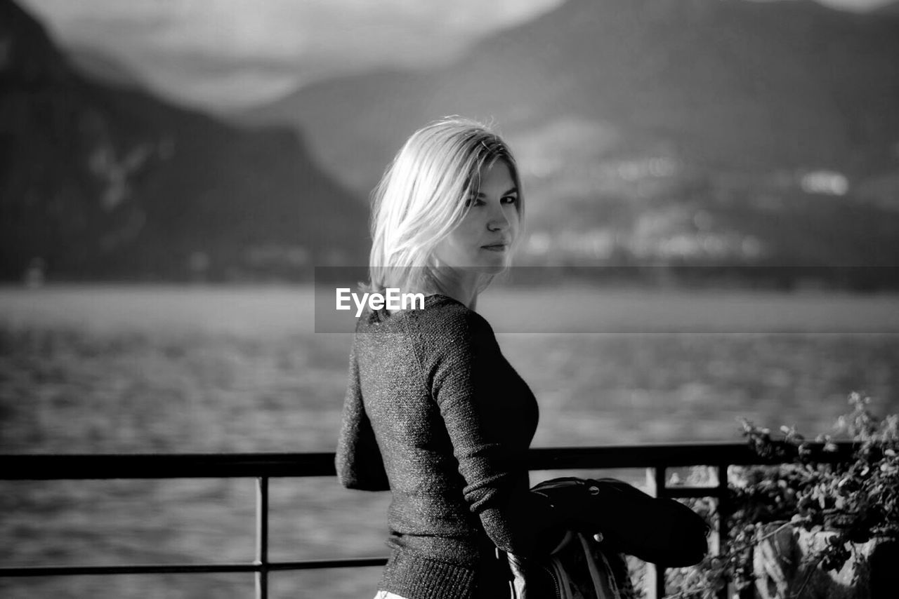 Woman standing by railing against sea