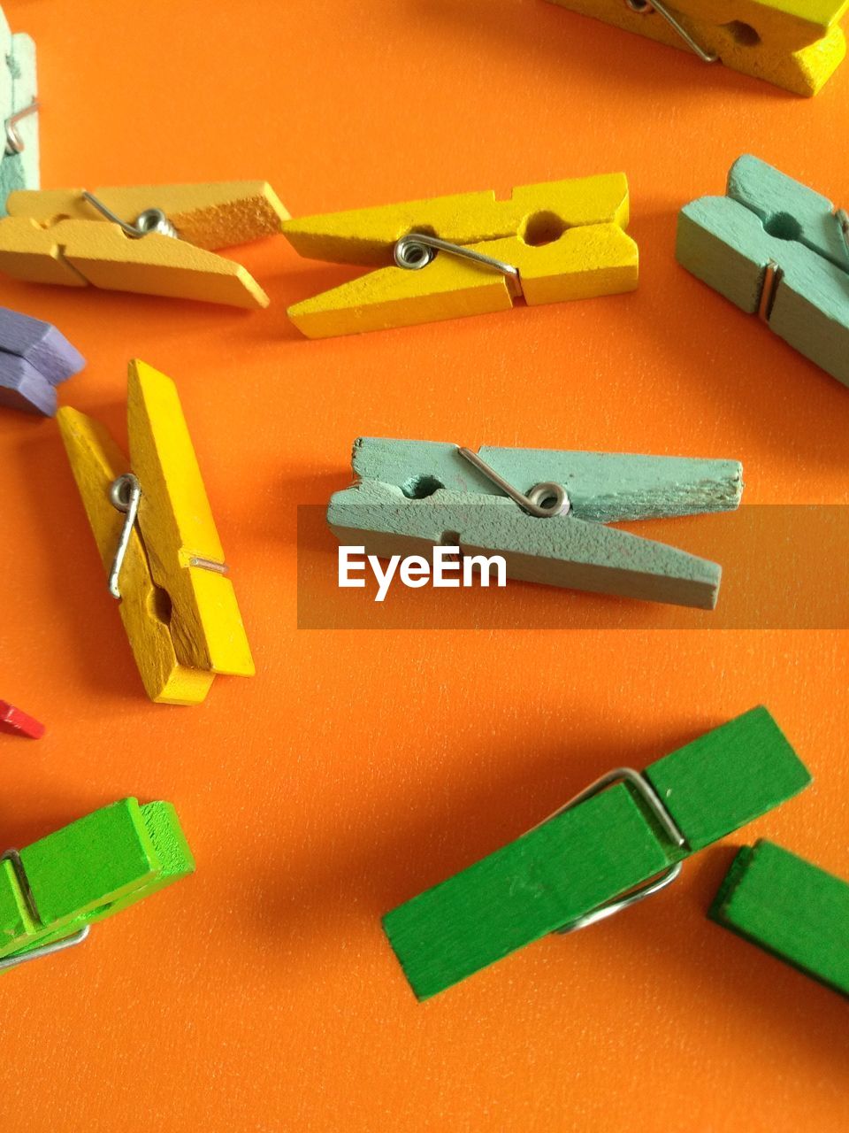 High angle view of colorful wooden clothespins on orange background