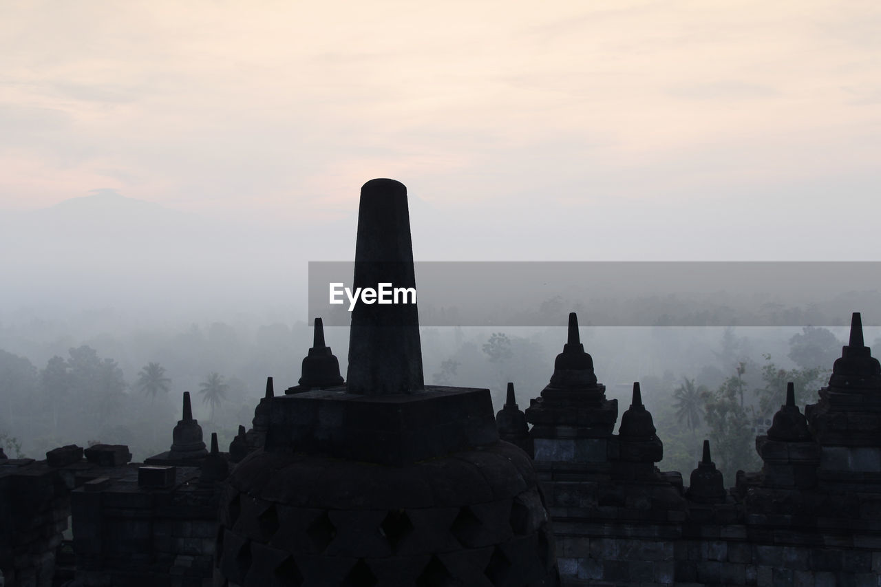 STUPAS OF TEMPLE AGAINST SKY DURING SUNSET