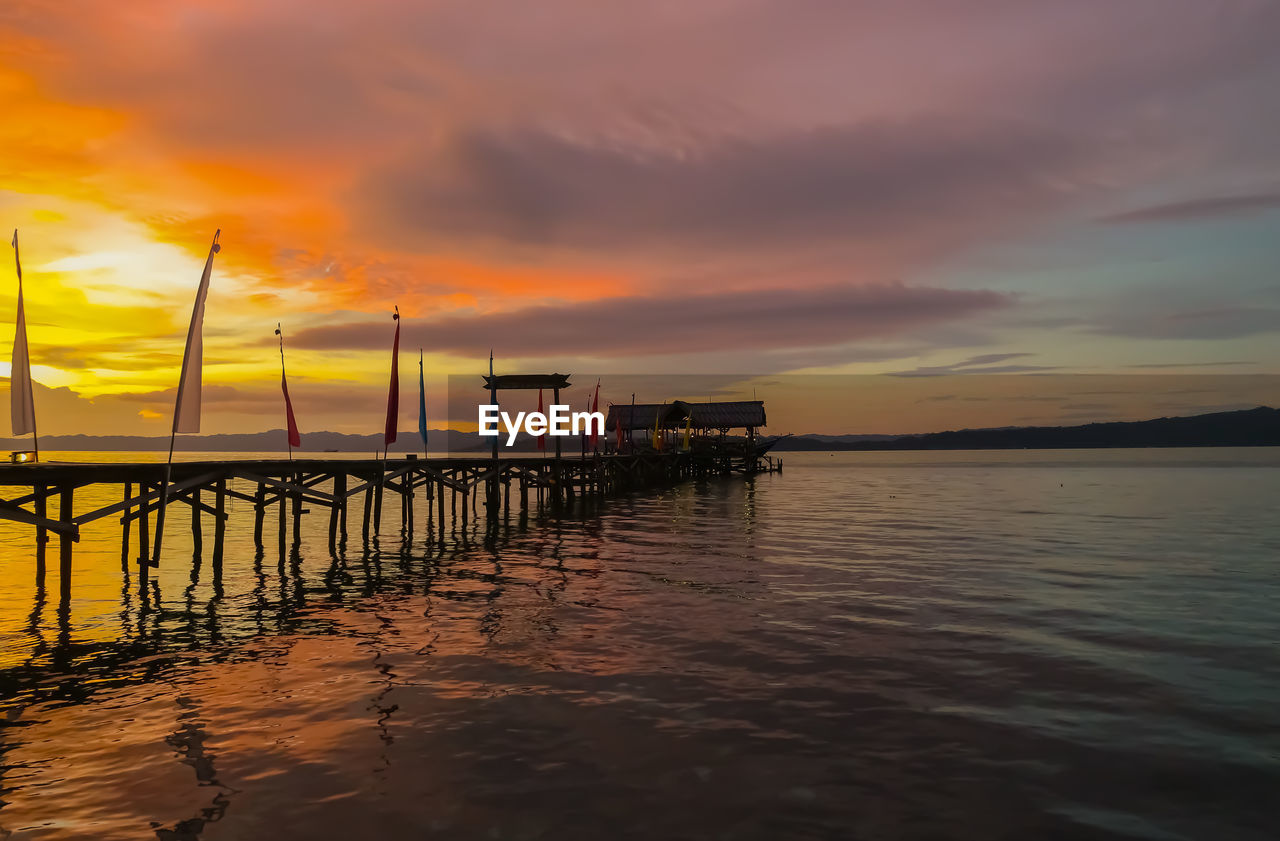 sky, water, cloud, sunset, sea, evening, reflection, beauty in nature, dusk, nature, pier, scenics - nature, horizon, tranquility, ocean, tranquil scene, architecture, shore, afterglow, beach, dramatic sky, land, sunlight, coast, no people, built structure, orange color, idyllic, outdoors, wave, environment, transportation, travel destinations, horizon over water, non-urban scene, wood, silhouette