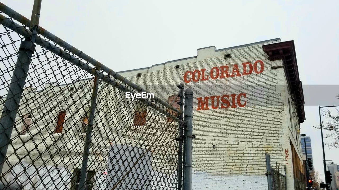 LOW ANGLE VIEW OF TEXT ON CHAINLINK FENCE