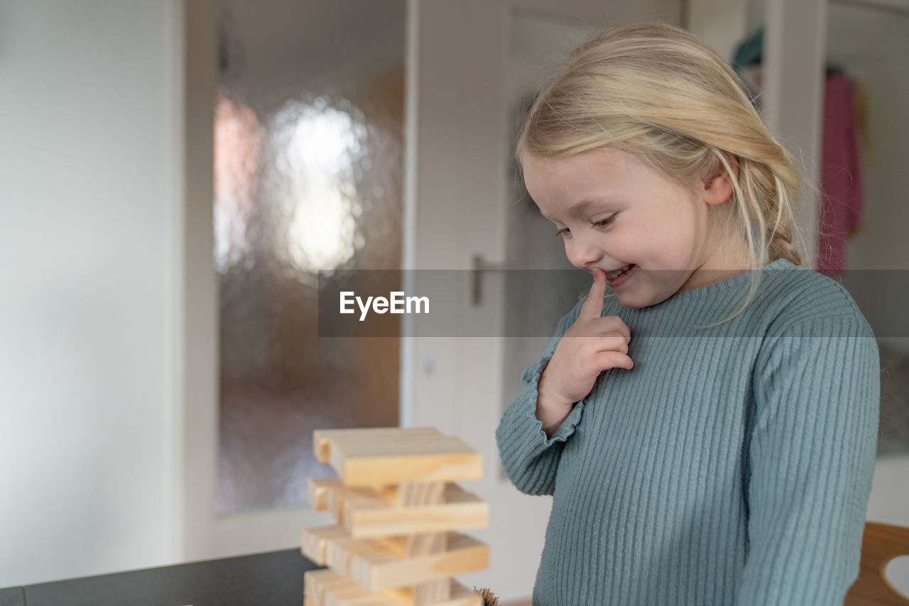 Toddler girl looks curiously on a wooden tower